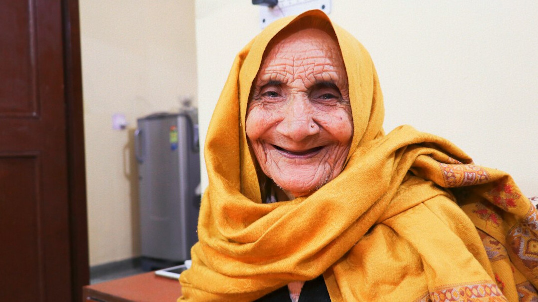 Elderly Danish woman smiling while waiting outdoors