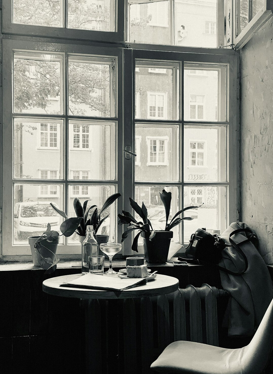 Person writing notes in a journal at a cafe table by a window